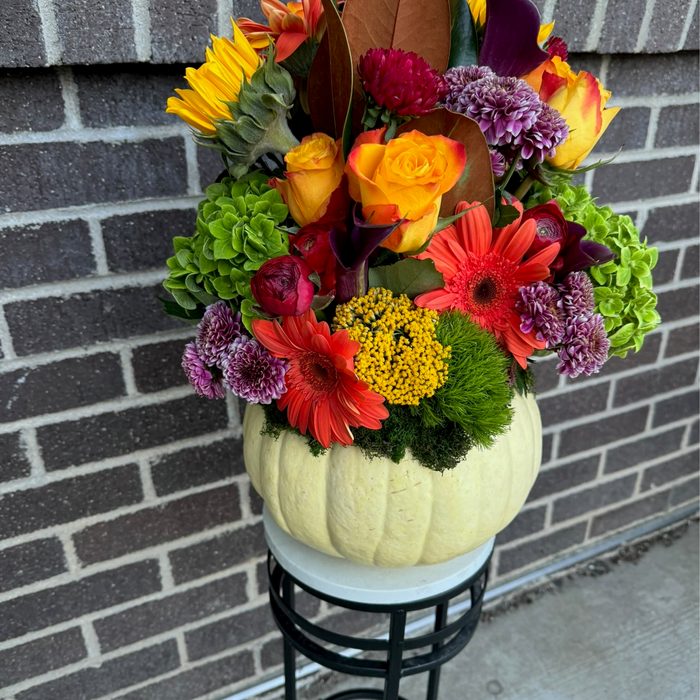 Autumn arrangement with gerberas, sunflowers, and mums in a white pumpkin