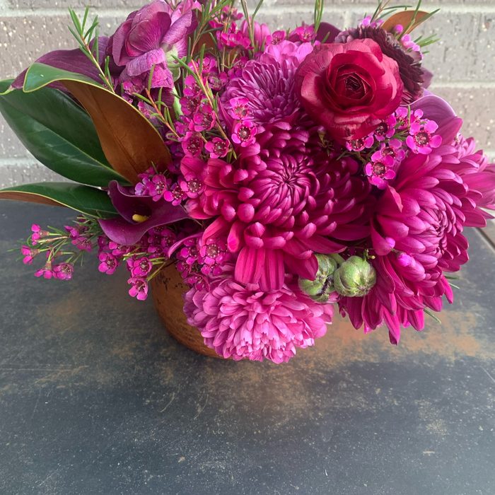 Magenta chrysanthemum and rose arrangement with magnolia foliage
