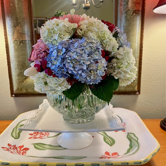 Blue and white hydrangea arrangement in a footed crystal bowl