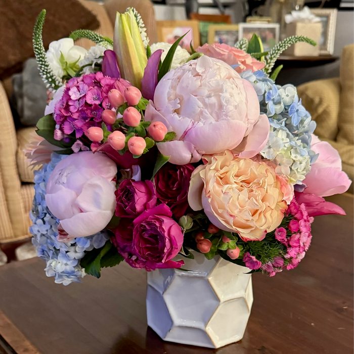 Pastel peony, garden rose, and hydrangea arrangement in a faceted vase