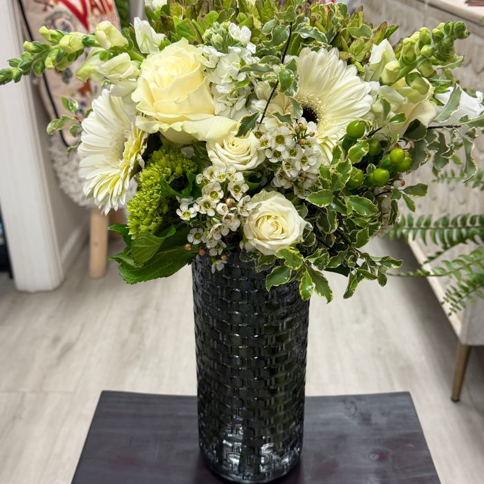 A classic white rose and cream gerbera arrangement in a dark vase
