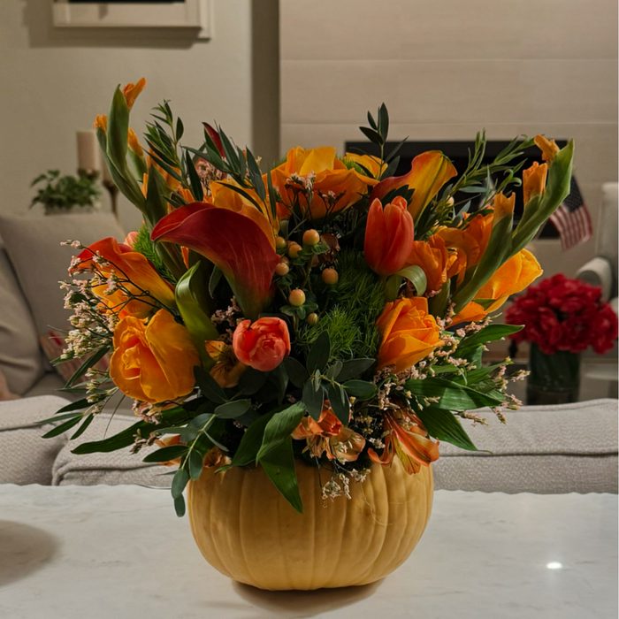 Orange roses, tulips, and calla lilies in a pumpkin vase