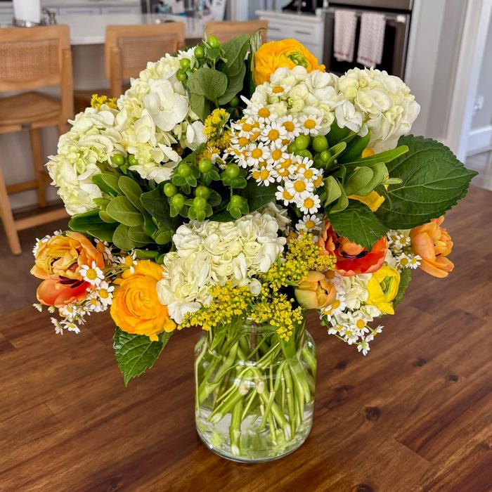 A bright cream and orange gift bouquet with hydrangea, daisies, and ranunculus