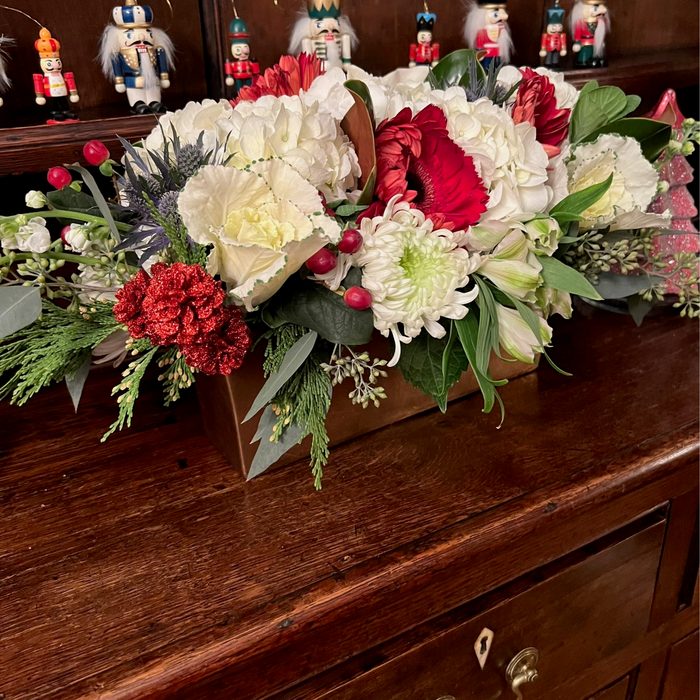 A red, white, and green Christmas centerpiece with magnolia and seeded eucalyptus