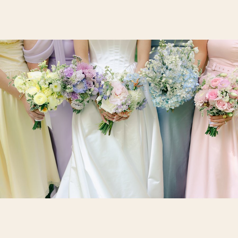 Bride and bridesmaids holding pastel bouquets in yellow, lavender, blush, and powder blue